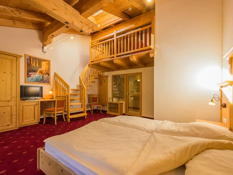 Maisonette-Zimmer mit Doppelbett, Dachfenster über der Galerie und rot gemustertem Teppichboden
